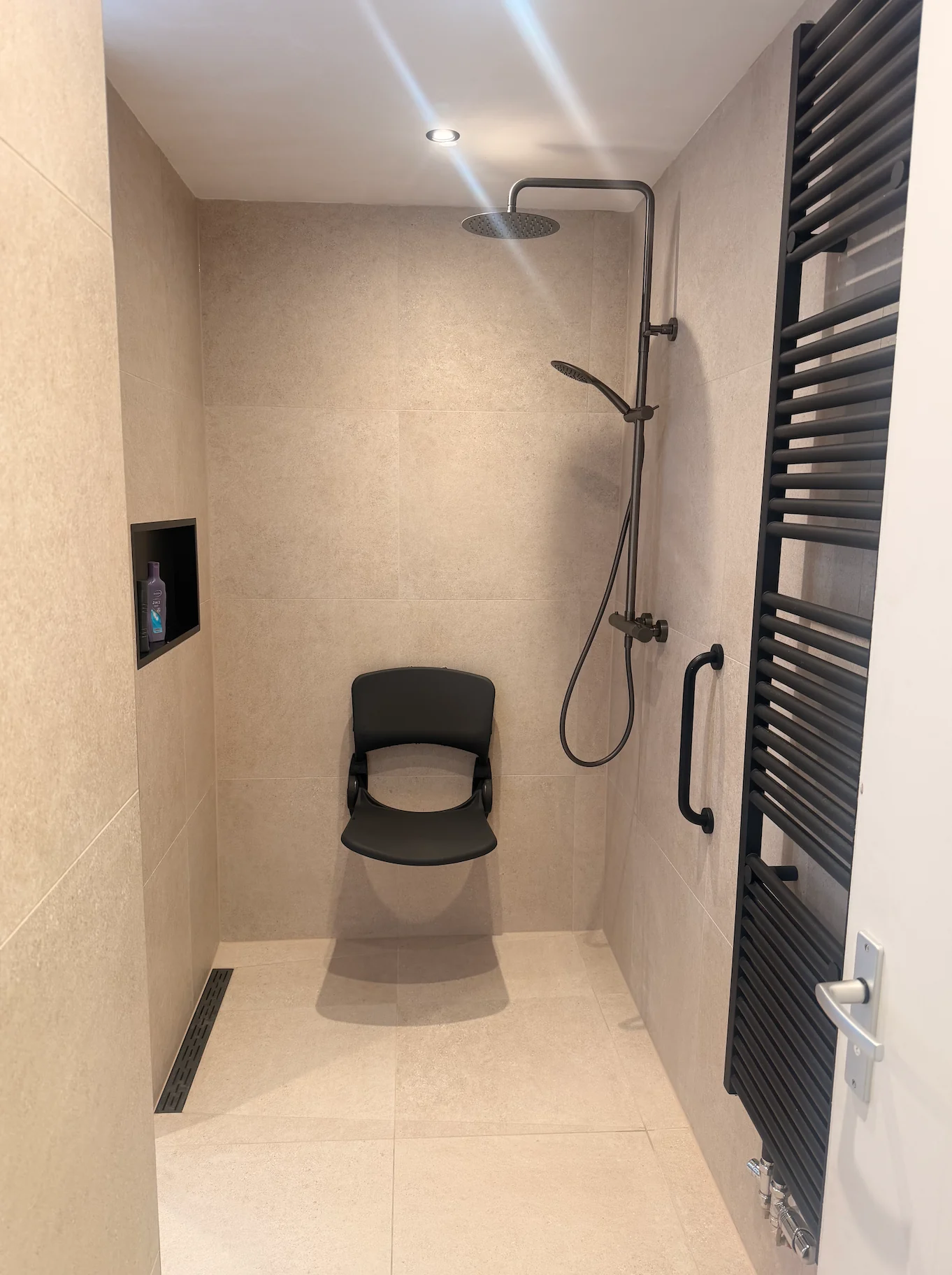Douche met douchestoel en steunbeugel in één van de gedeelde badkamers